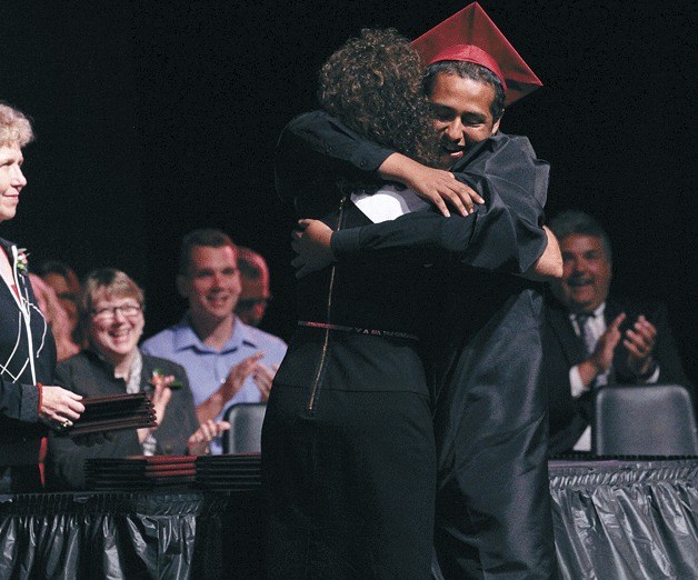 Secondary Academy for Success student Danny Castro gives principal Donna Tyo a hug during the high school graduation ceremony.