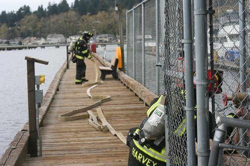 Two Northshore Fire Department firefighters display the Harbour Village Marina's updated fire-suppression system this afternoon in Kenmore.