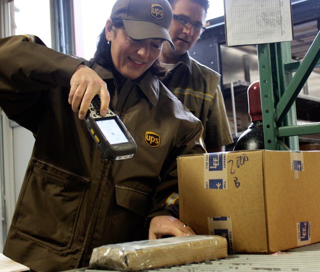 Congresswoman Suzan DelBene scans a package while UPS delivery driver Mike Vallimont watches on Wednesday morning at Triumph Aerospace Group on Redmond Ridge.