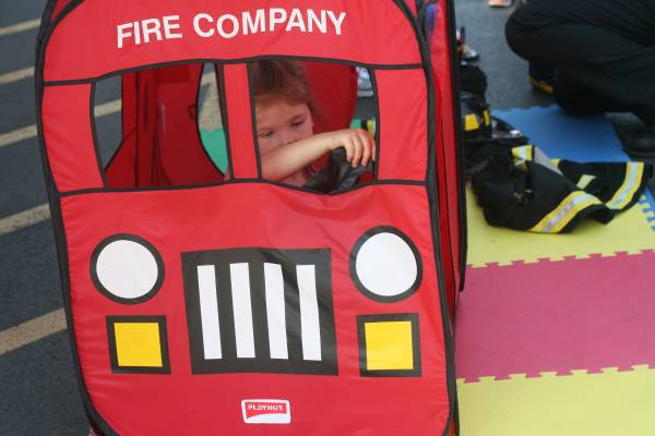 Sage Comstock of Kenmore concentrates on steering a play fire truck at the Bothell Fire Department booth Sunday afternoon at the downtown Bothell RiverFest event.