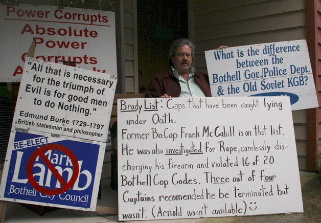 Bothell resident James Barnhart sits with his signs