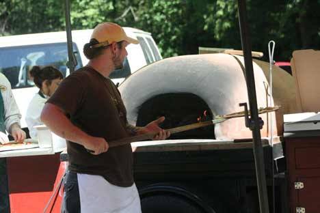 Daniel Nelon of Veraci Pizza of Ballard checks the pizza he’s making in a wood-fired oven in the Blyth parking lot. Nelon and his co-workers Aric Fehrenbacher and Elena Arntz were at the park to cater a business party. Nelon said he had the oven firing at 1