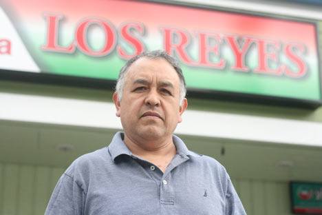 Mario Reyes stands tall in front of his grocery store.